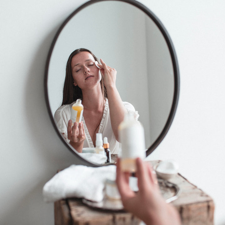 woman applying makeup remover on cotton pad to face