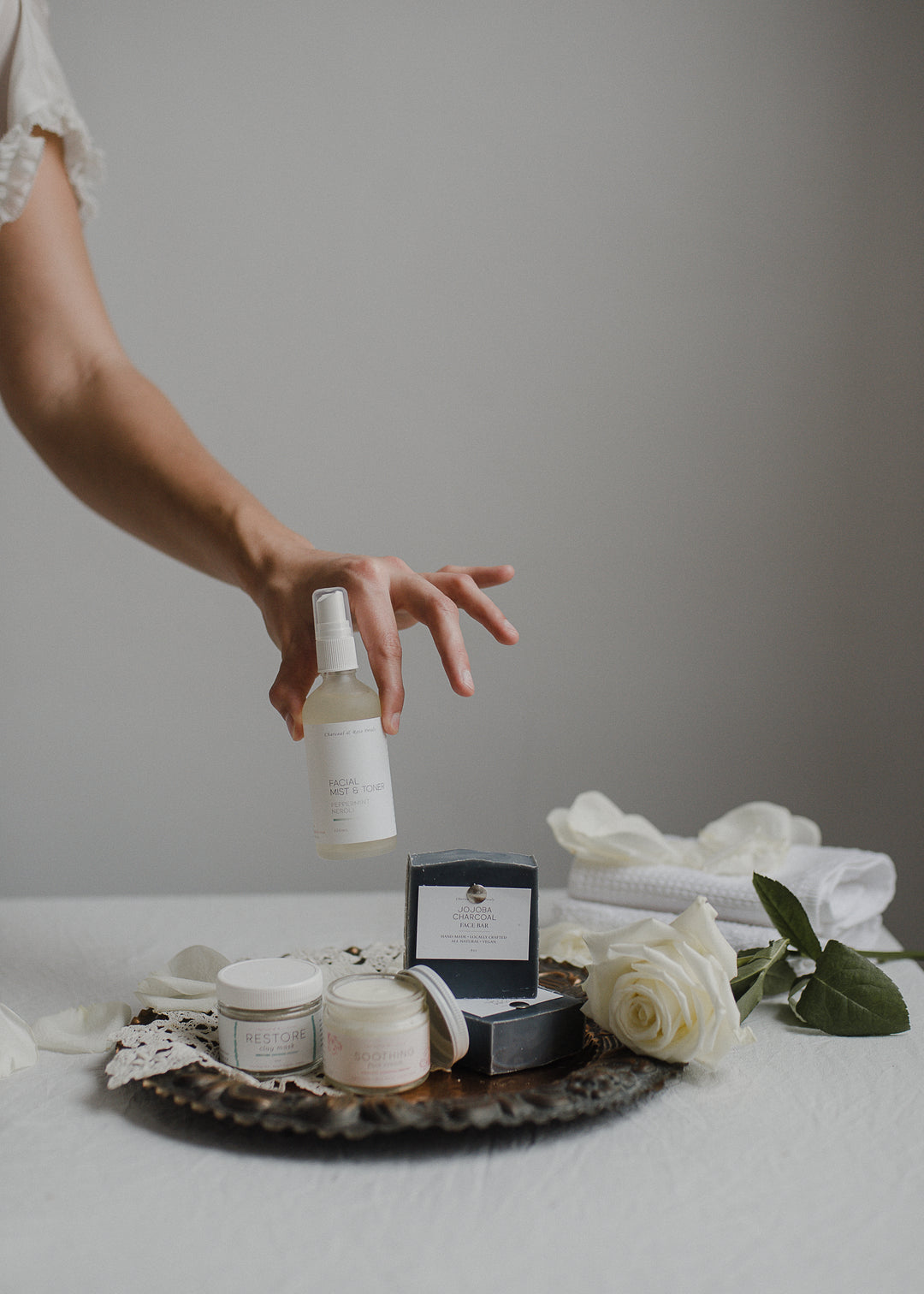 face products on tray hand holding facial mist & toner