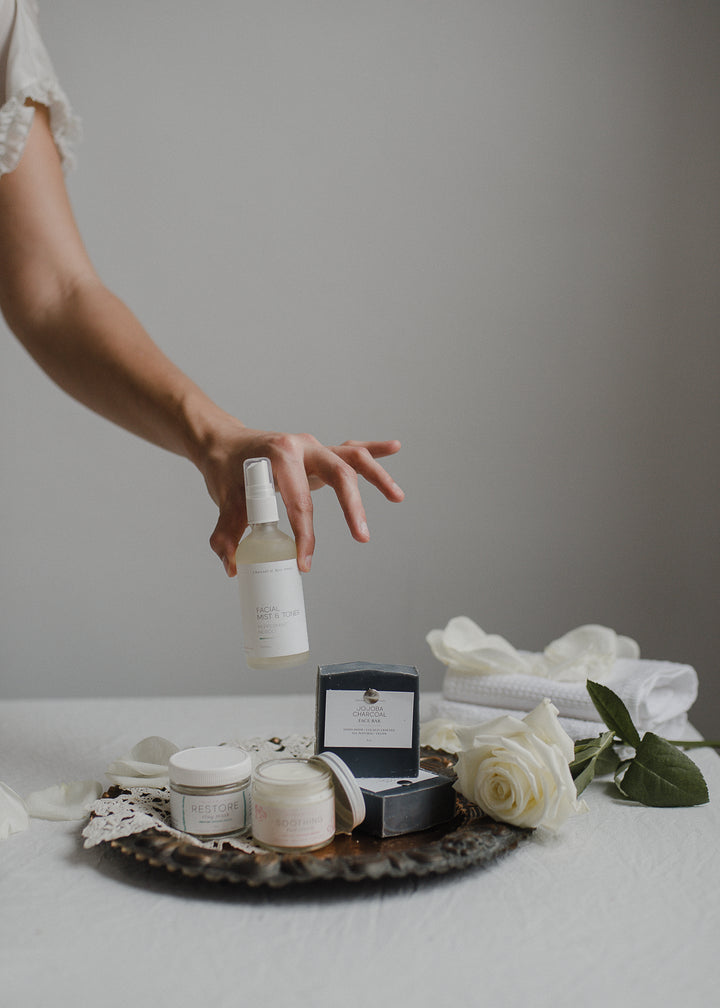 face products on tray hand holding facial mist & toner